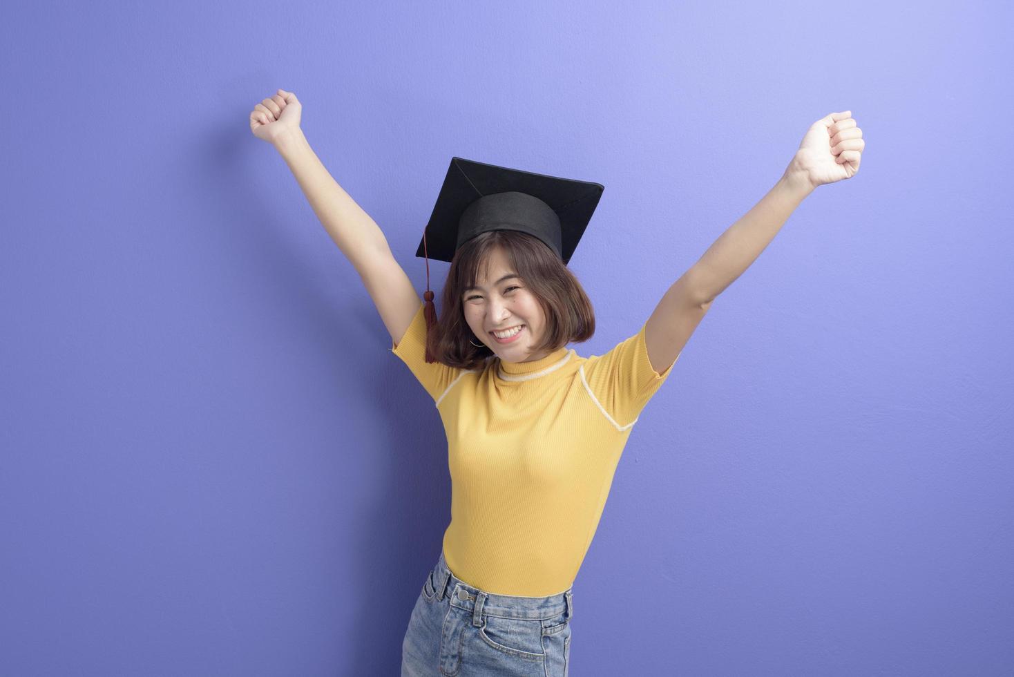 porträtt av ung asiatisk student som bär examensmössa över studiobakgrund. foto