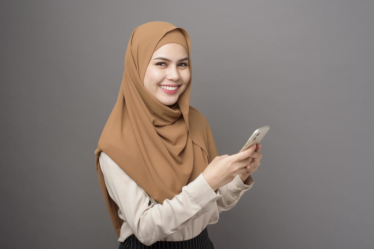 porträtt av vacker kvinna med hijab ler på grå bakgrund foto