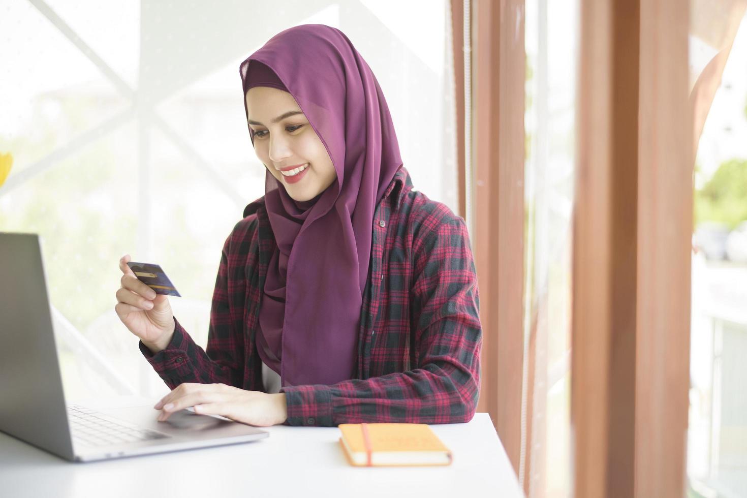 muslimsk kvinna med hijab arbetar med bärbar dator i kaféet foto