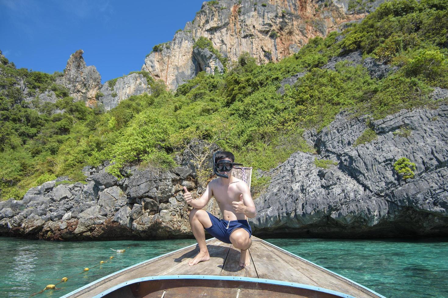 en aktiv man på thailändsk traditionell longtailbåt är redo att snorkla och dyka, phi phi-öarna, thailand foto