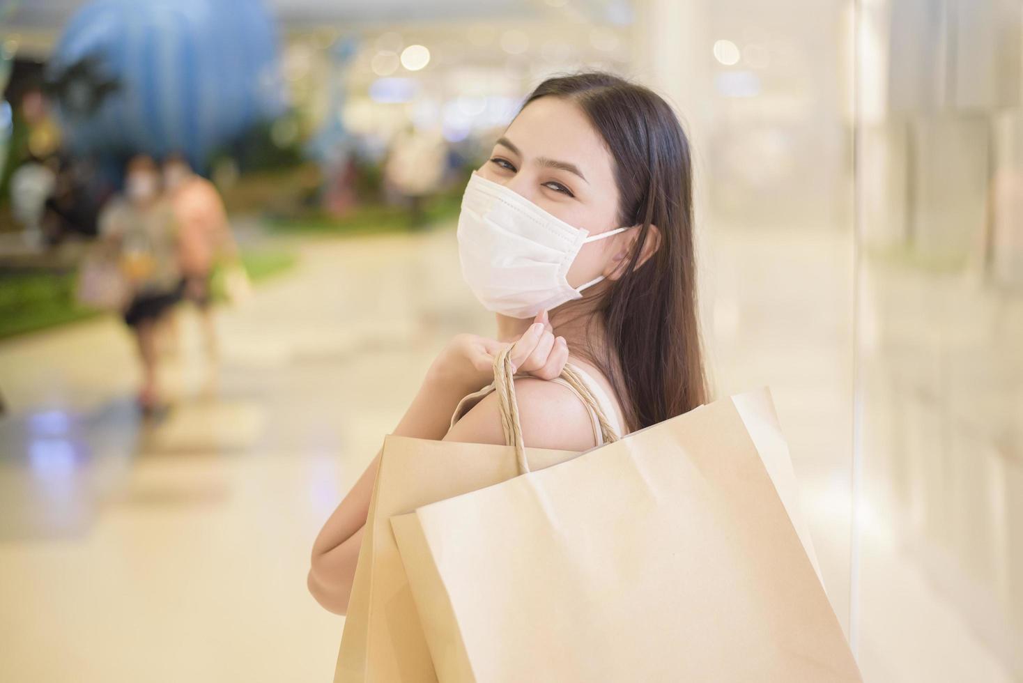 porträtt av vacker kvinna bär ansiktsmask i köpcentrum foto