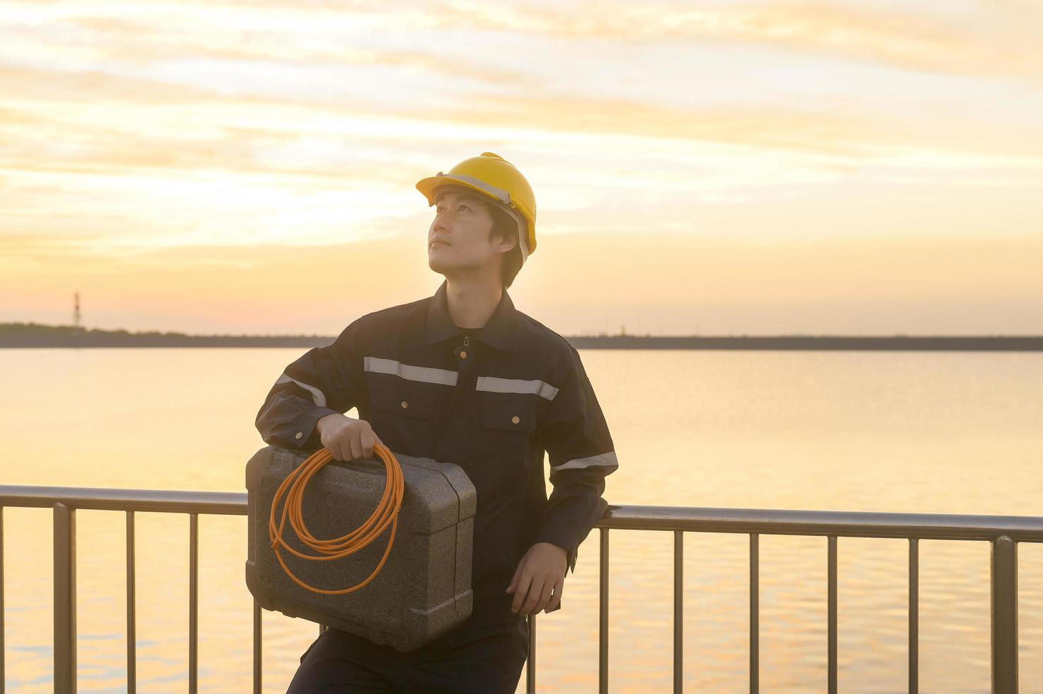 en manlig ingenjör som bär skyddshjälm vid solnedgången. foto