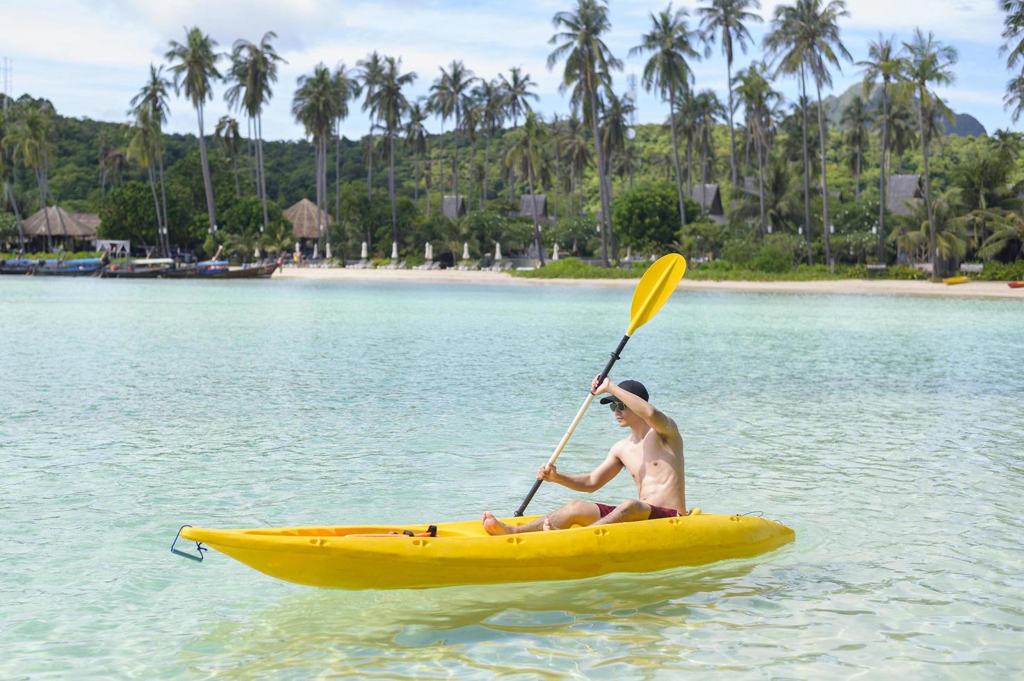 en ung sportig man som paddlar kajak vid havet i en solig dag foto