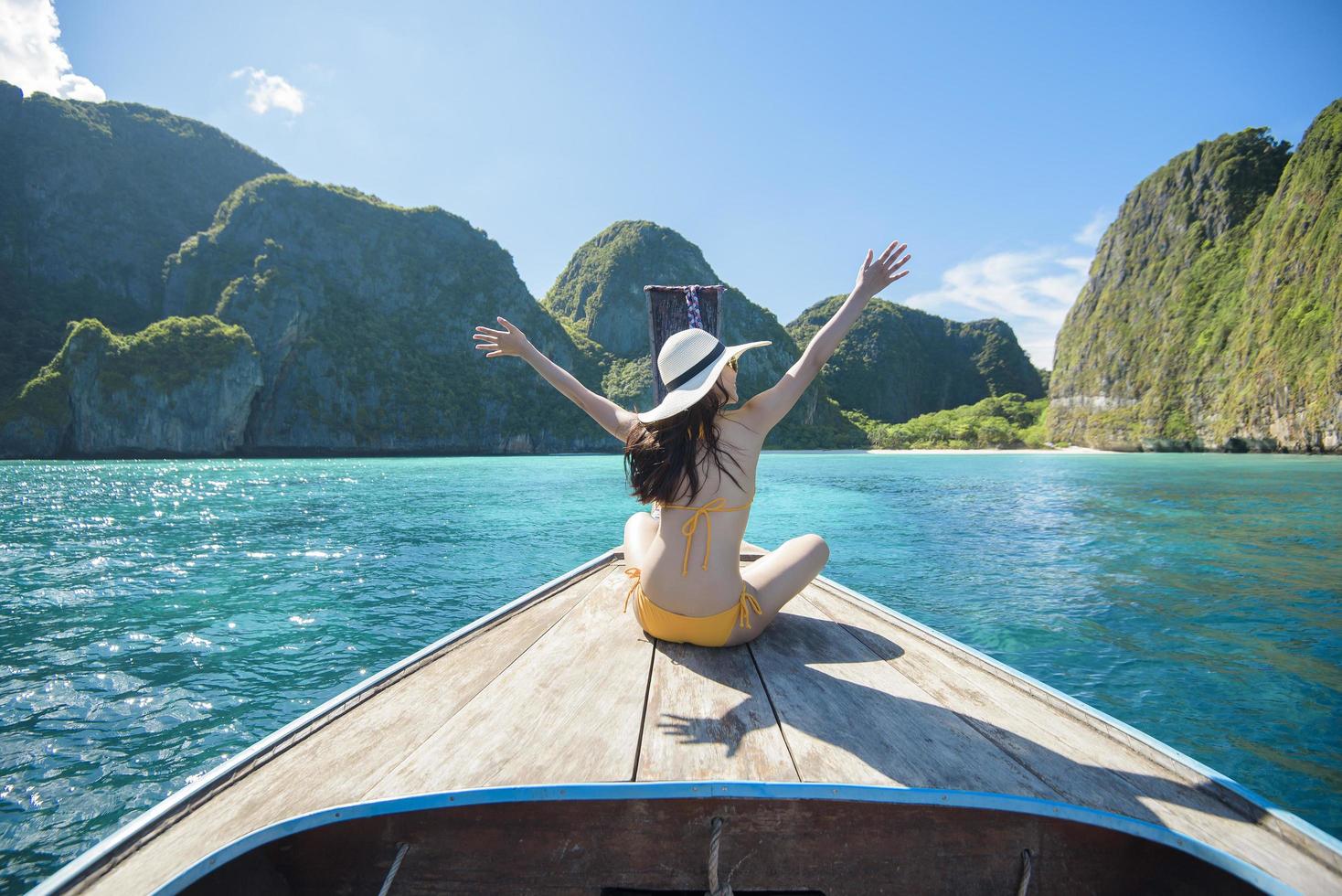 utsikt över kvinna i baddräkt som njuter på thailändsk traditionell longtailbåt över vackra berg och hav, phi phi-öarna, thailand foto