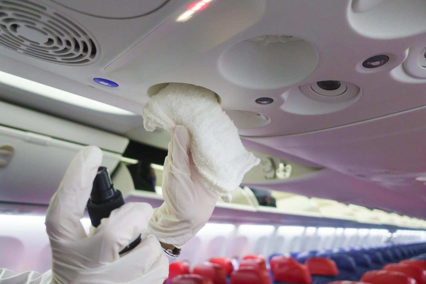 Närbild hand bär handskar rengöring flygplan för covid-19 förebyggande pandemi foto