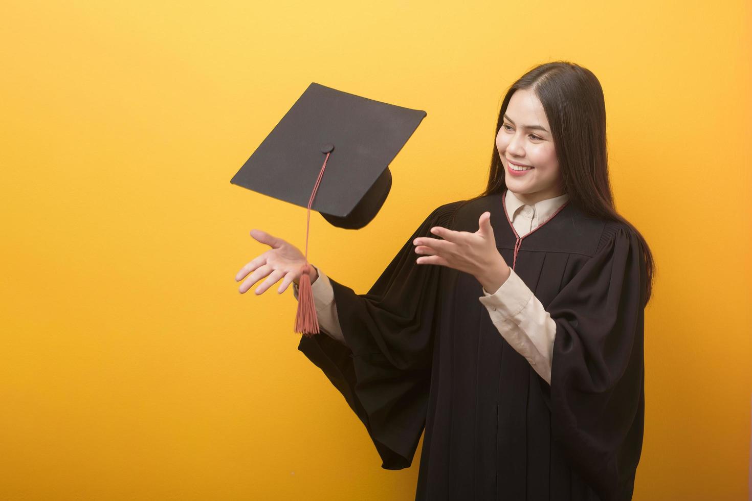 porträtt av glad vacker kvinna i examen klänning på gul bakgrund foto