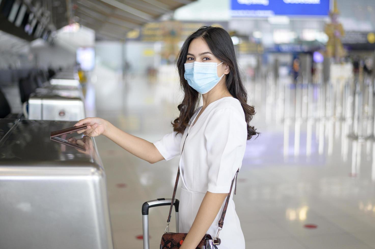 en resenskvinna bär skyddsmask på den internationella flygplatsen, resor under covid-19-pandemin, säkerhetsresor, socialt avståndsprotokoll, nytt normalt resekoncept foto