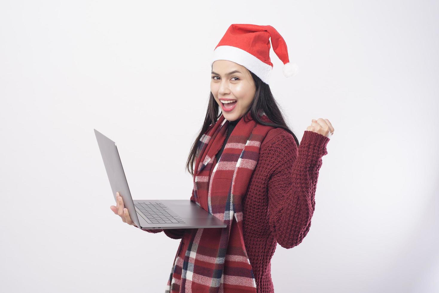 ung leende kvinna bär röd jultomte hatt ringer videosamtal på sociala nätverk med familj och vänner på vit bakgrund studio. foto