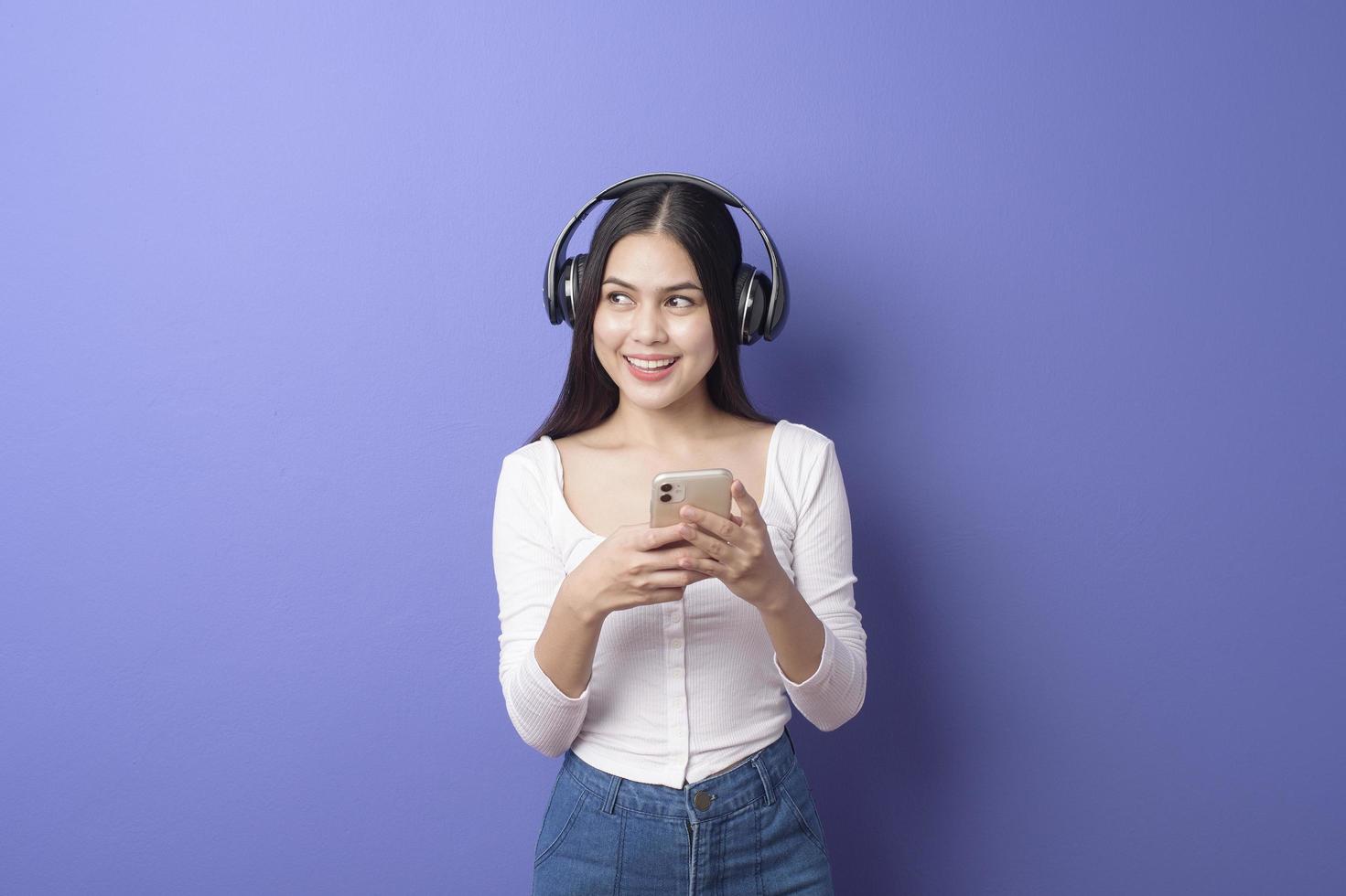 ung kvinna lyssnar på musik på lila bakgrund foto