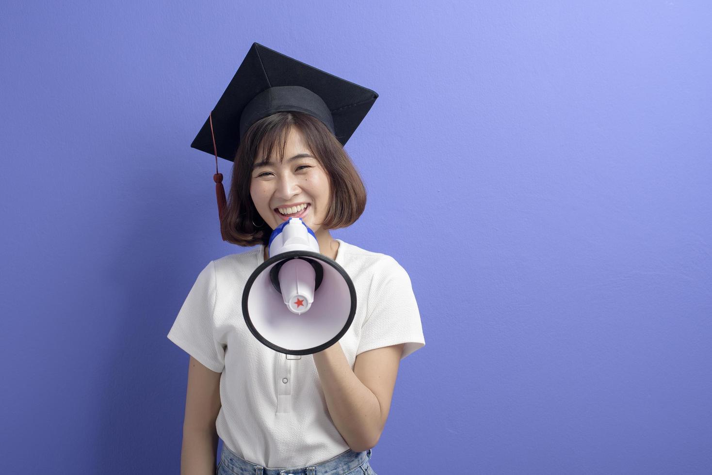 porträtt av examen asiatisk student håller megafon isolerade lila bakgrund studio foto