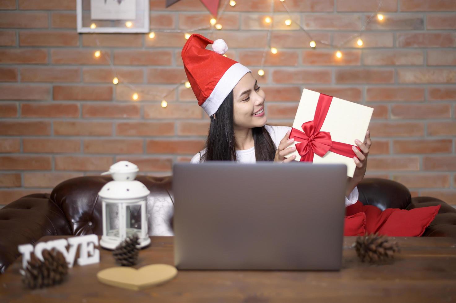 ung leende kvinna som bär röd jultomtehatt ringer videosamtal på sociala nätverk med familj och vänner på juldagen. foto