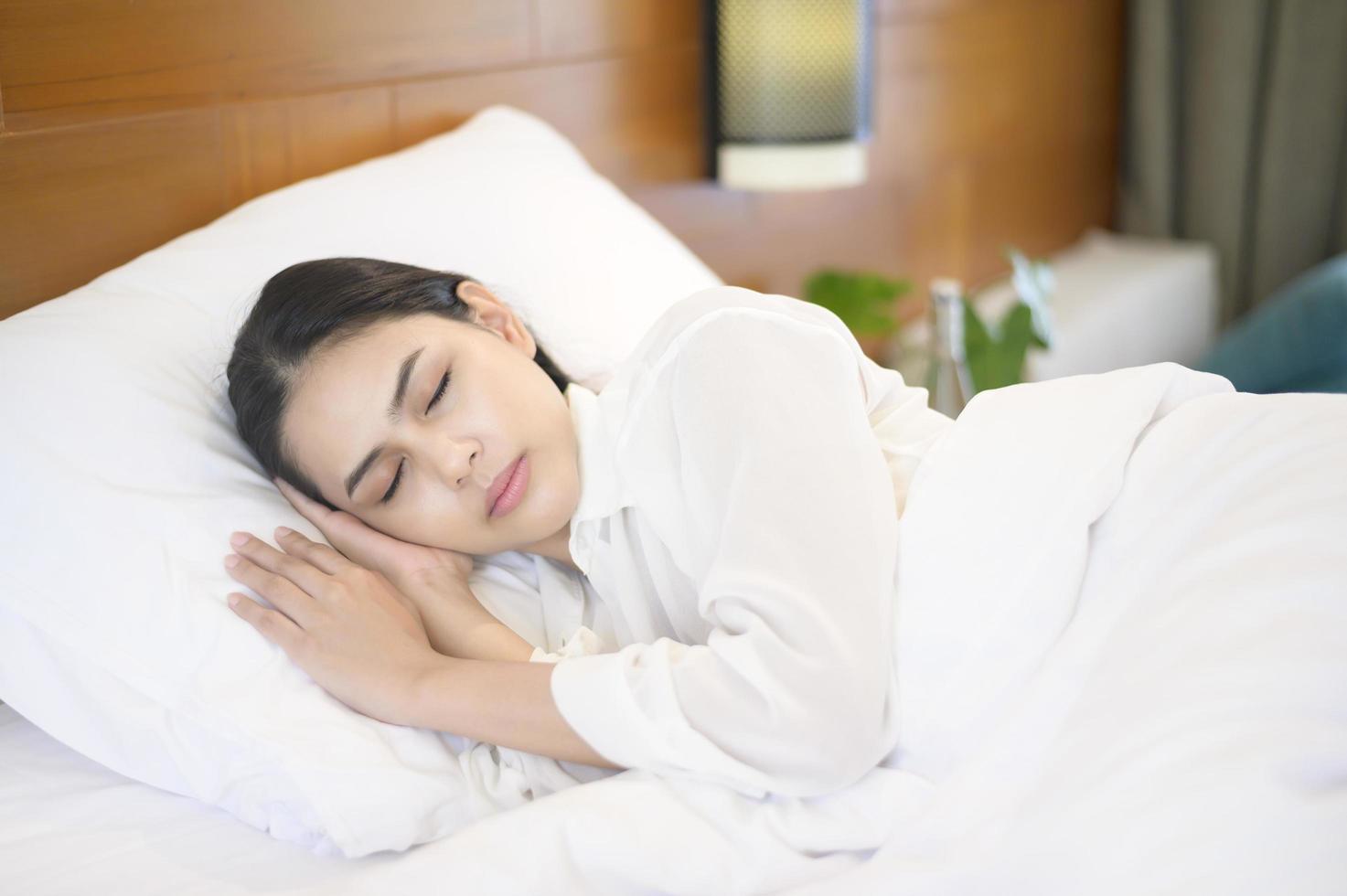 ung vacker kvinna som sover i sin säng hemma foto