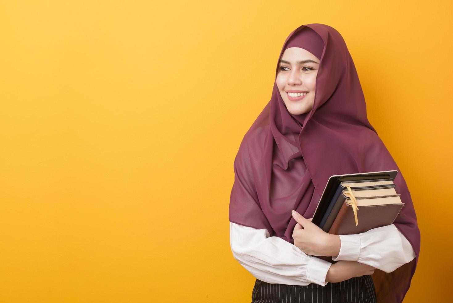 vacker universitetsstudent med hijab porträtt på gul bakgrund foto