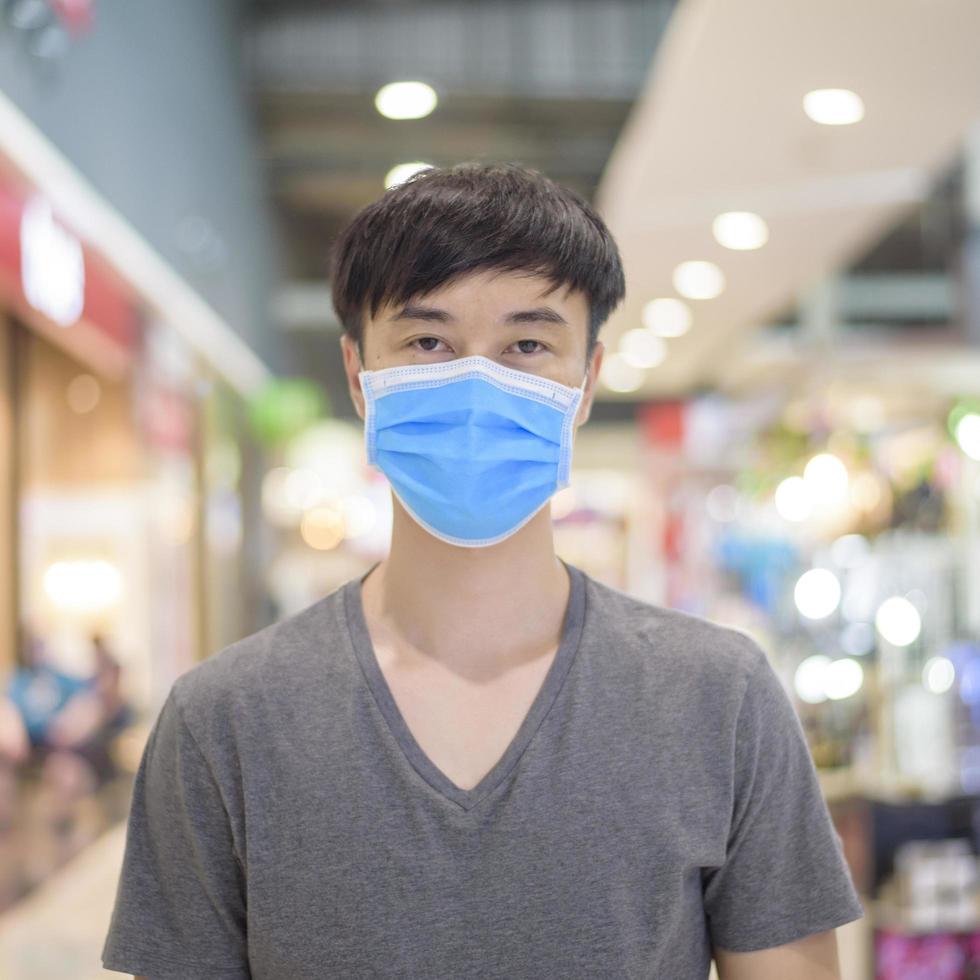 asiatisk man bär kirurgisk mask i köpcentrum foto