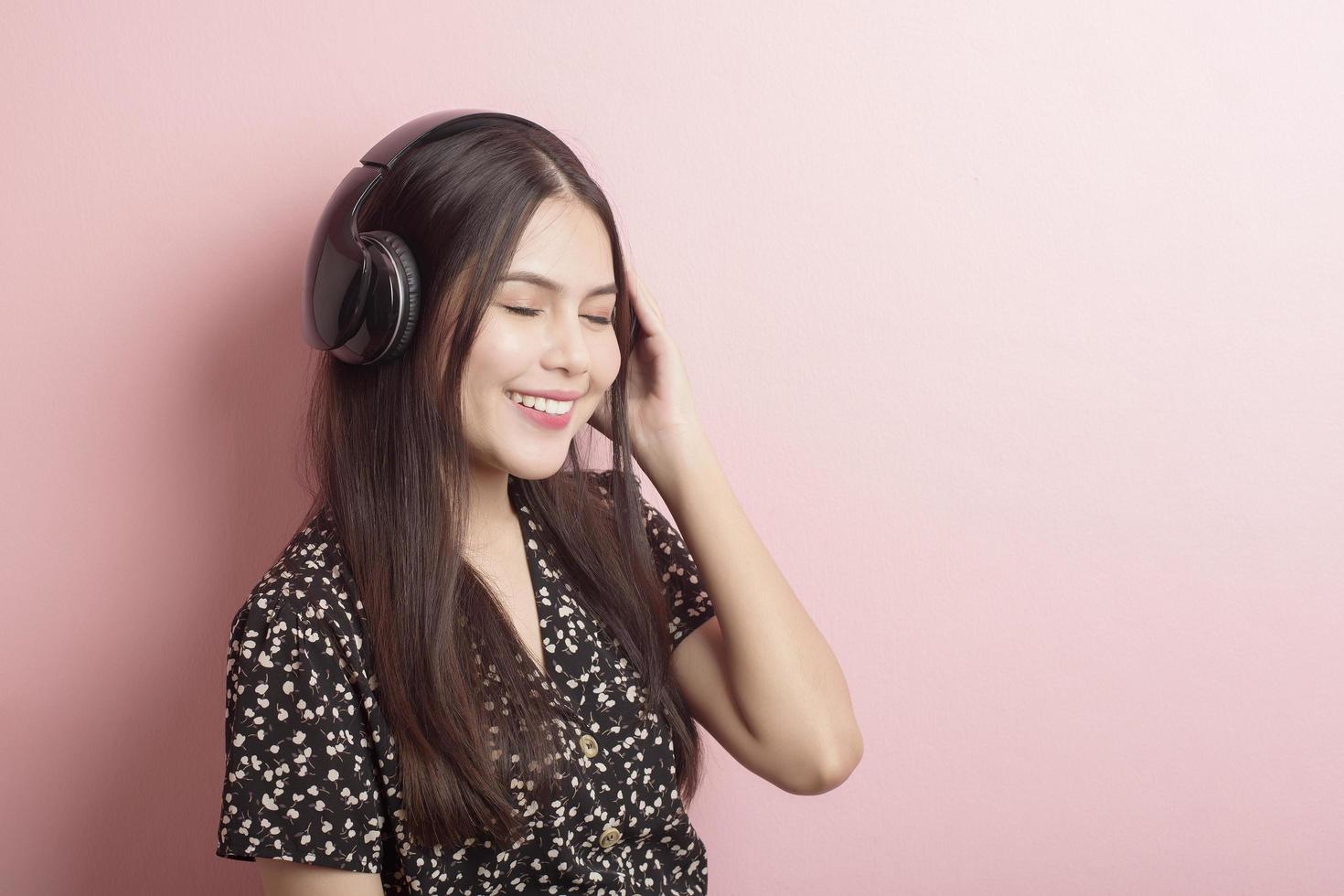 musikälskare kvinnan njuter med headsetet på rosa bakgrund foto