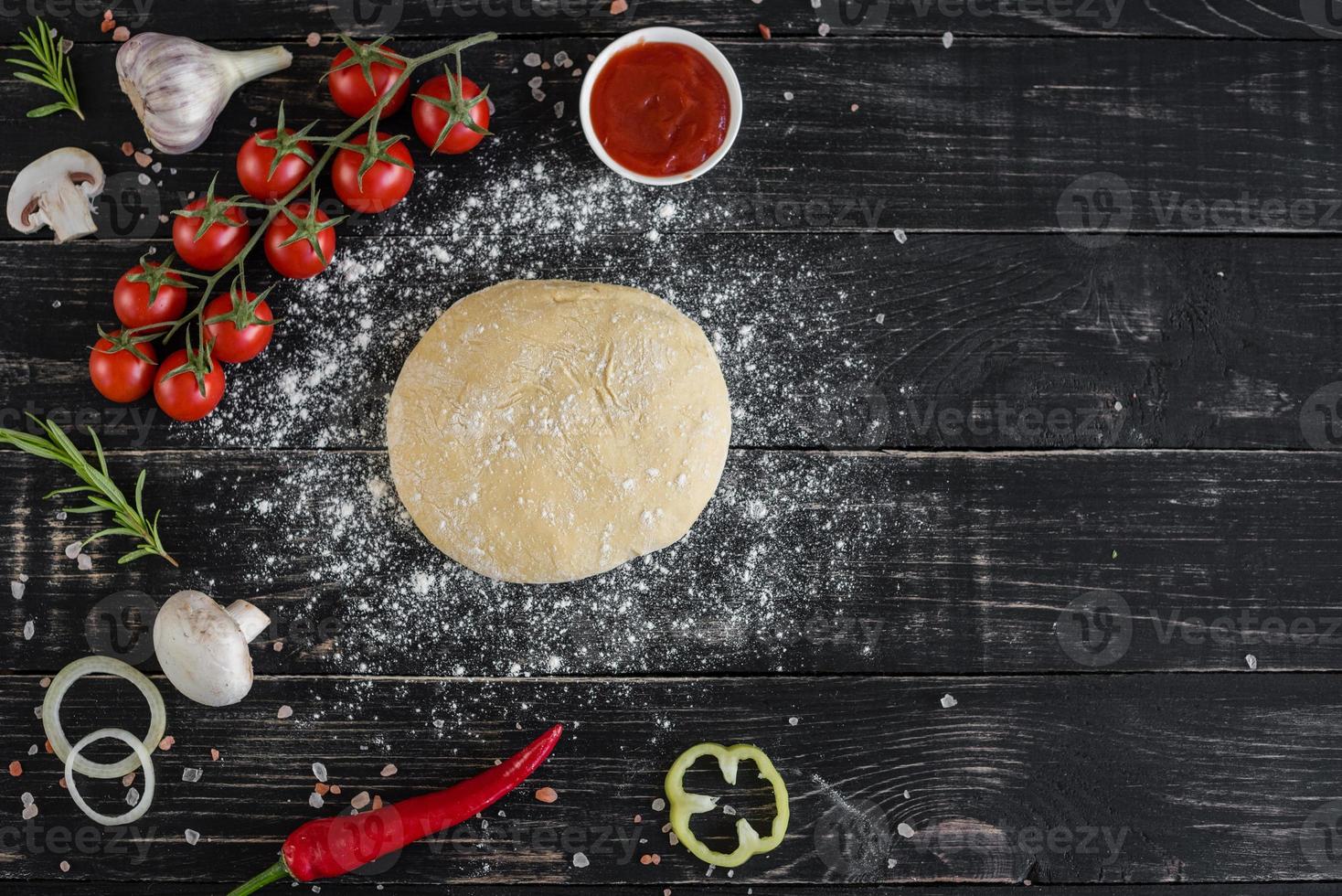 rå deg för pizza med ingredienser och kryddor på svart bakgrund foto