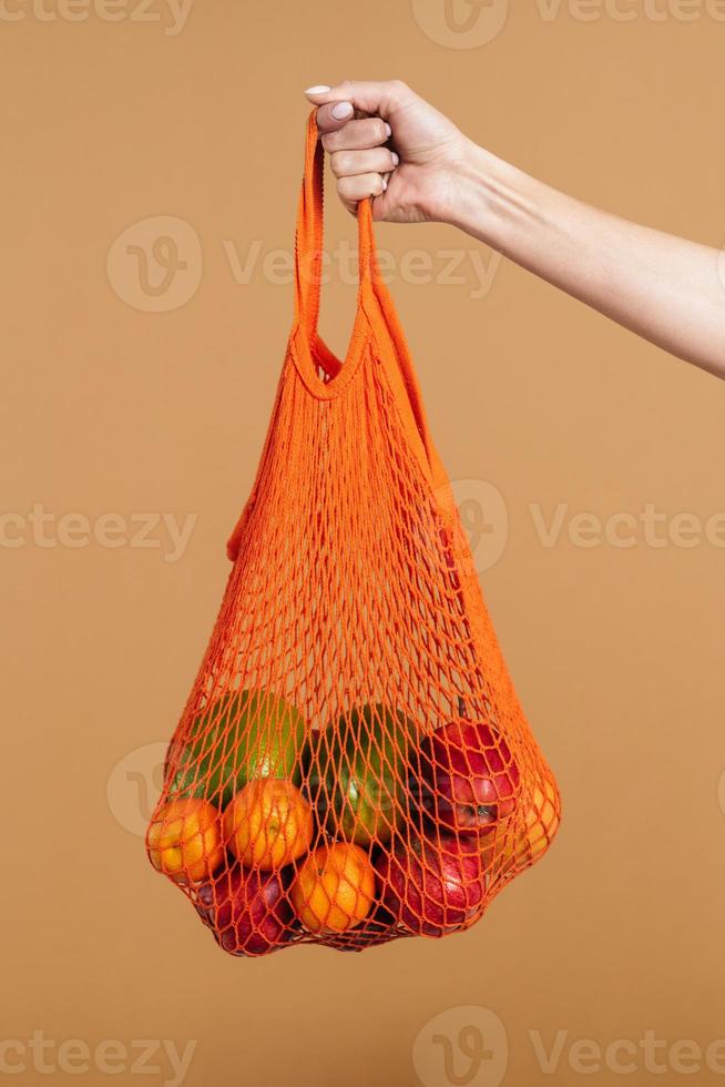 kvinna med återanvändbar orange fruktpåse foto