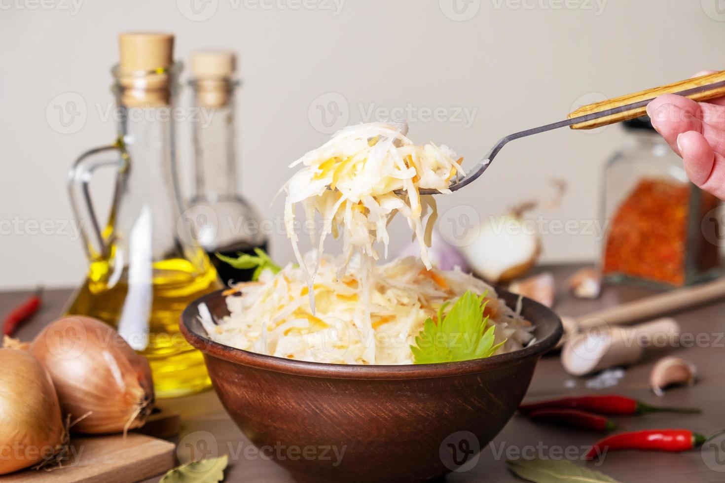 fermenterad kål i keramisk skål på bordet med kryddor och ingredienser foto