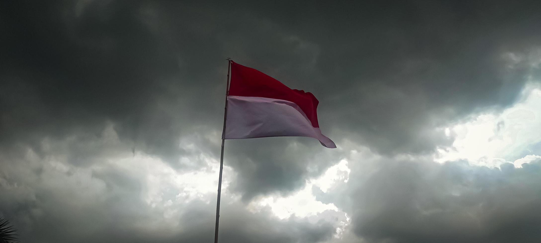 indonesiska flaggan fladdrar mot en molnig himmel bakgrund foto