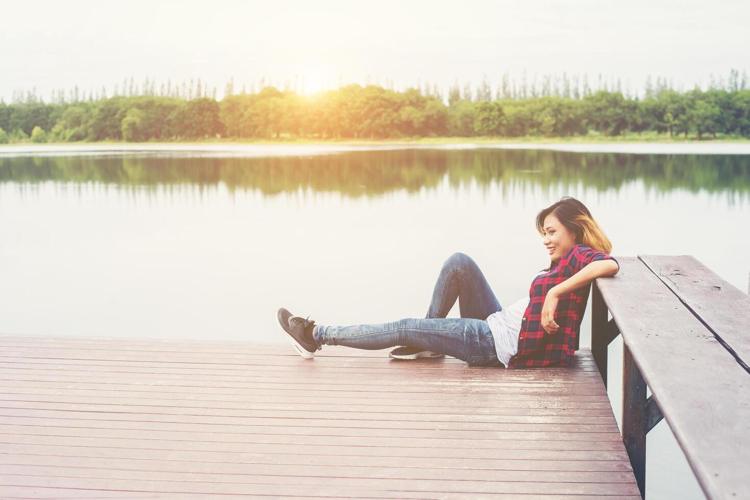 ung hipster kvinna sitter på träbrygga, avkopplande. foto