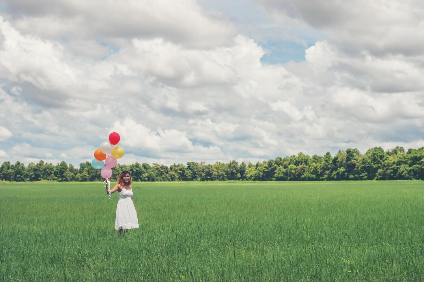 glad ung vacker kvinna med ballonger i gräsfältet njuta med frisk luft. foto