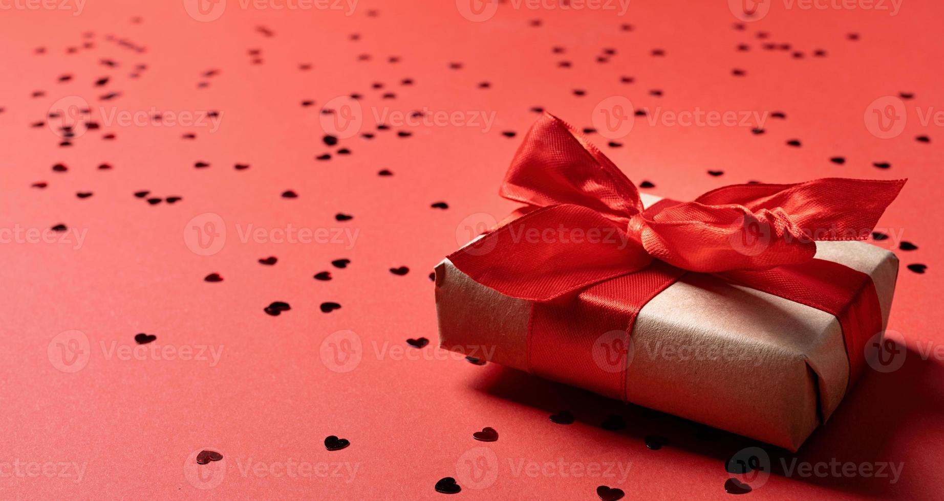 röd presentförpackning med ett band för alla hjärtans dag som firar på röd solid bakgrund med kopia utrymme foto