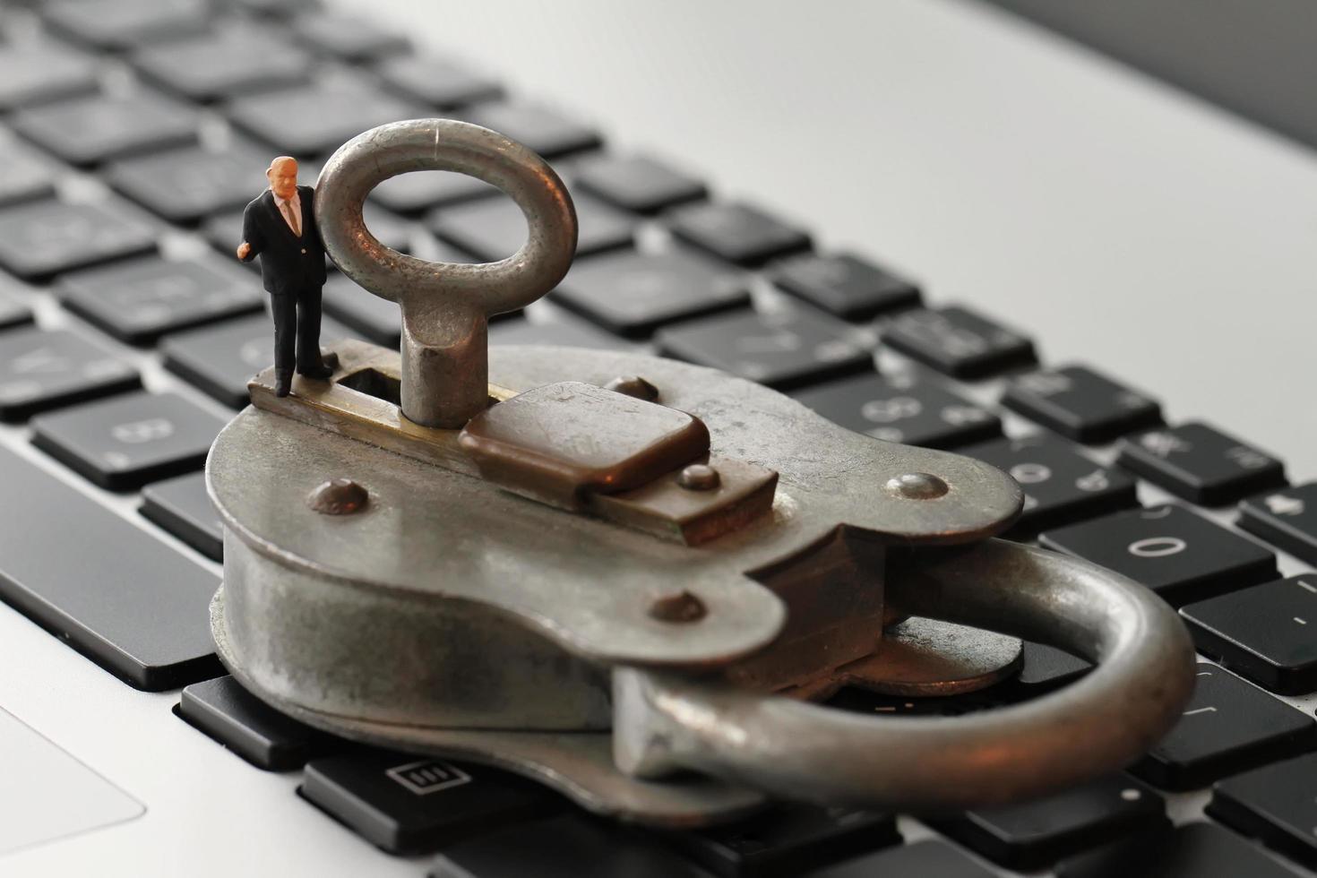 Internetsäkerhet koncept-miniatyr affärsman stå på gammal nyckel och hänglås på bärbar dators tangentbord foto