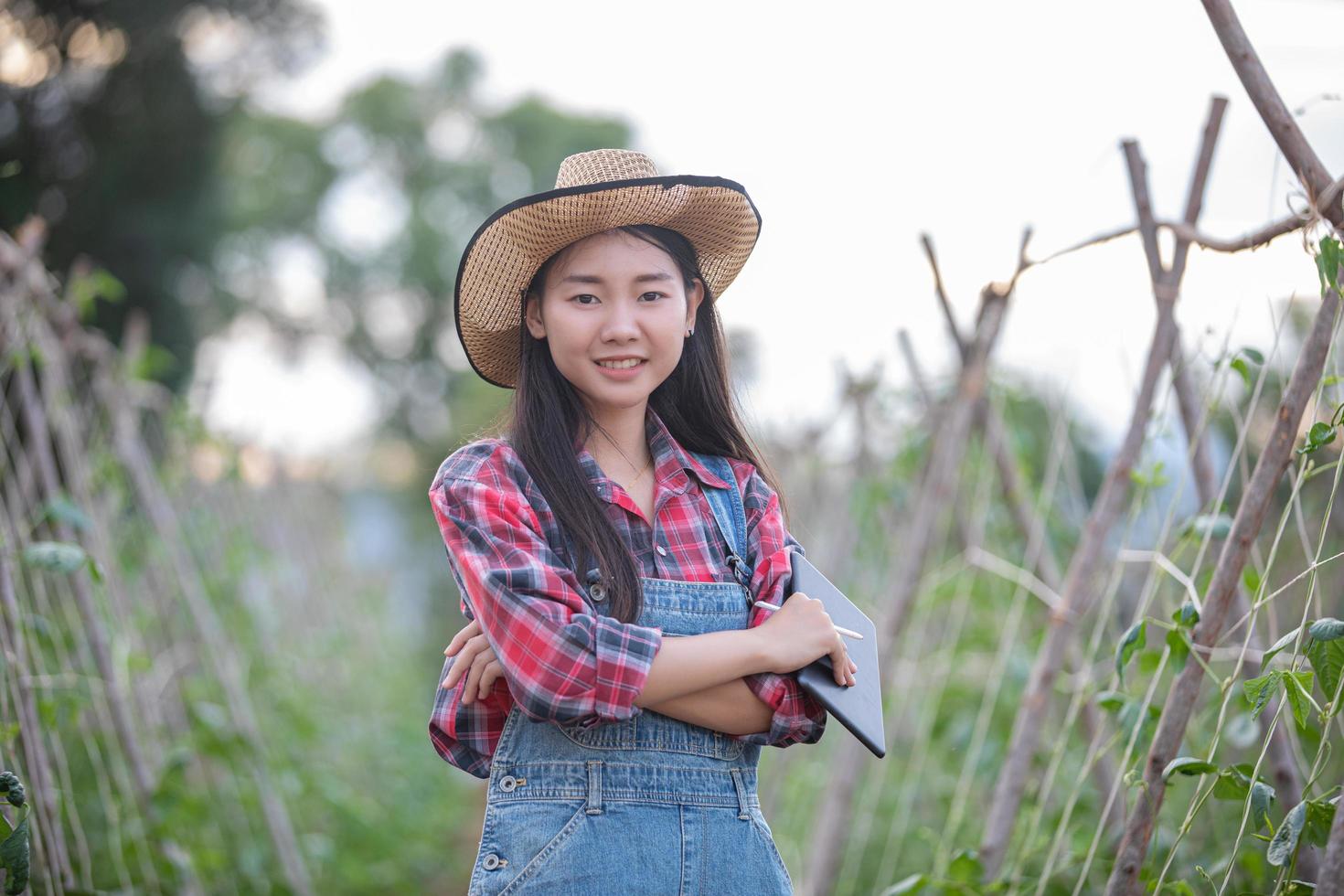 Asiatiska kvinnliga agronomer och lantbrukare som använder teknik för inspektion i jordbruks- och ekologiska grönsaksfält foto