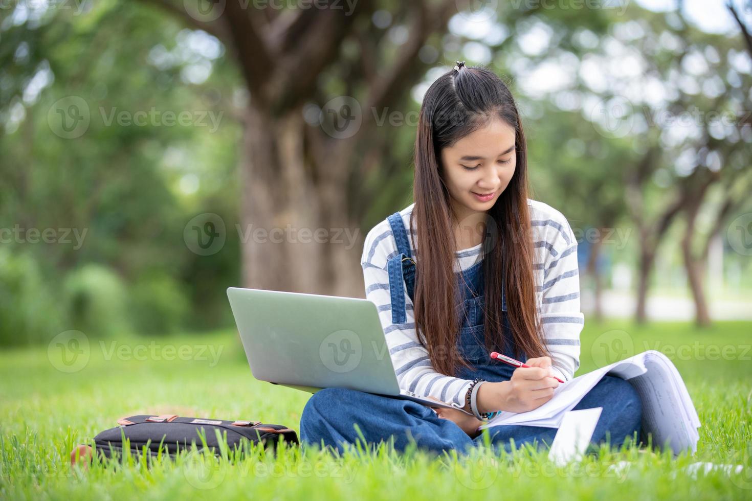 vacker asiatisk tjejstudent håller böcker och ler mot kameran och lärande och utbildningskoncept på parken på sommaren för avkopplingstid foto