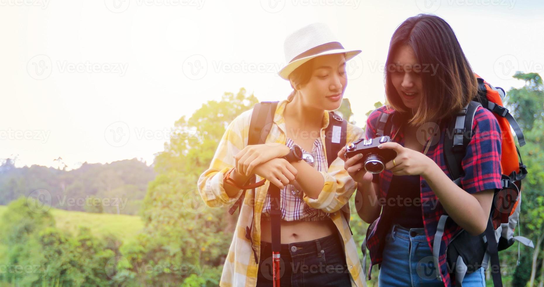 asiatisk grupp ungdomar som vandrar med vänner ryggsäckar går tillsammans och tittar på karta och tar fotokamera vid vägen och ser lyckliga ut, slappna av på semester konceptresor foto