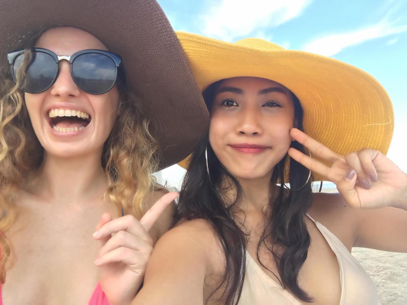 kvinnor tar foton och selfies med vänner på sandstranden på sommaren.