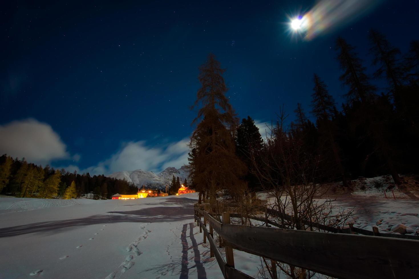 hus i snön på en stjärnklar natt med månen foto