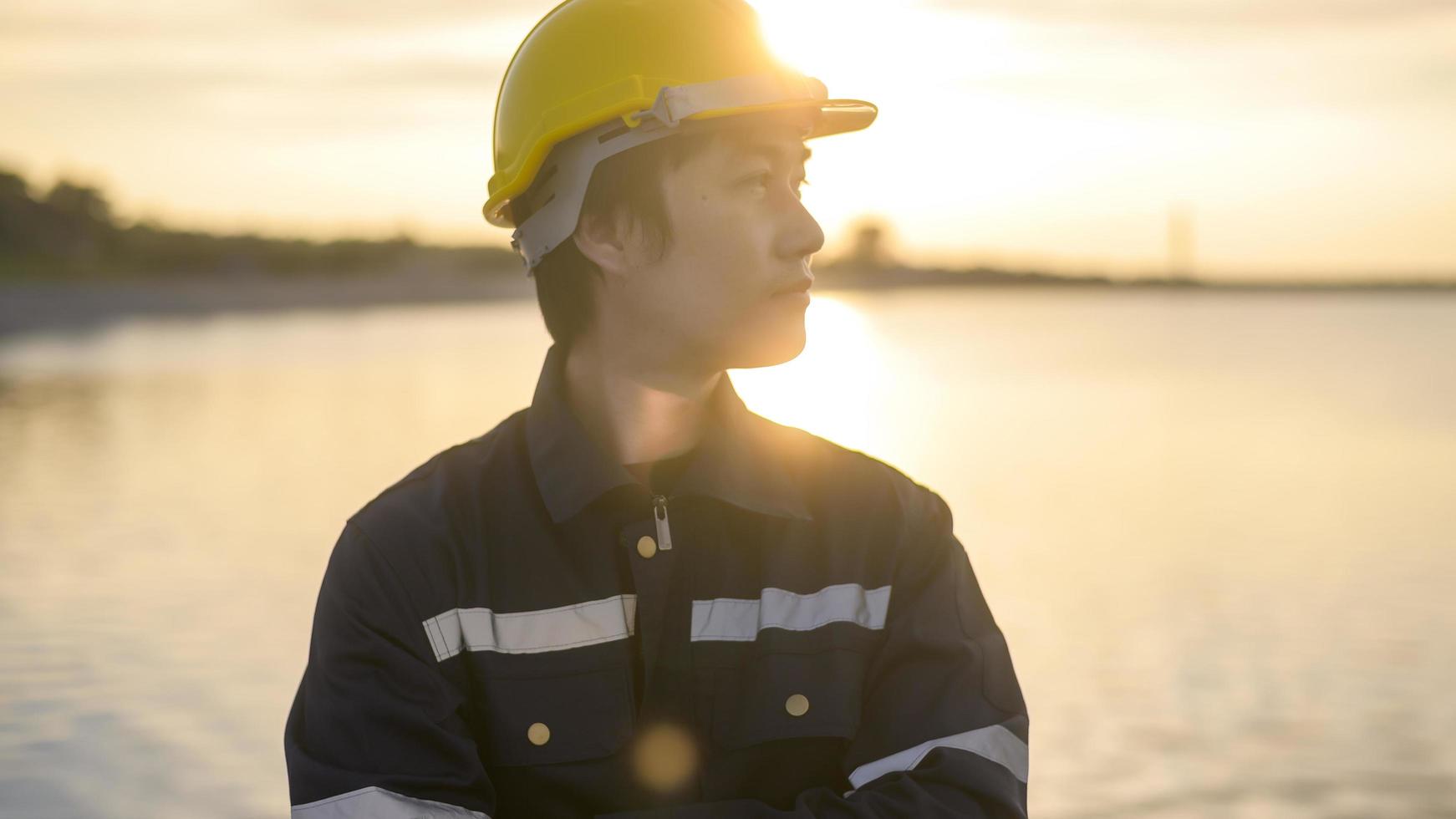 en manlig ingenjör som bär skyddshjälm vid solnedgången. foto