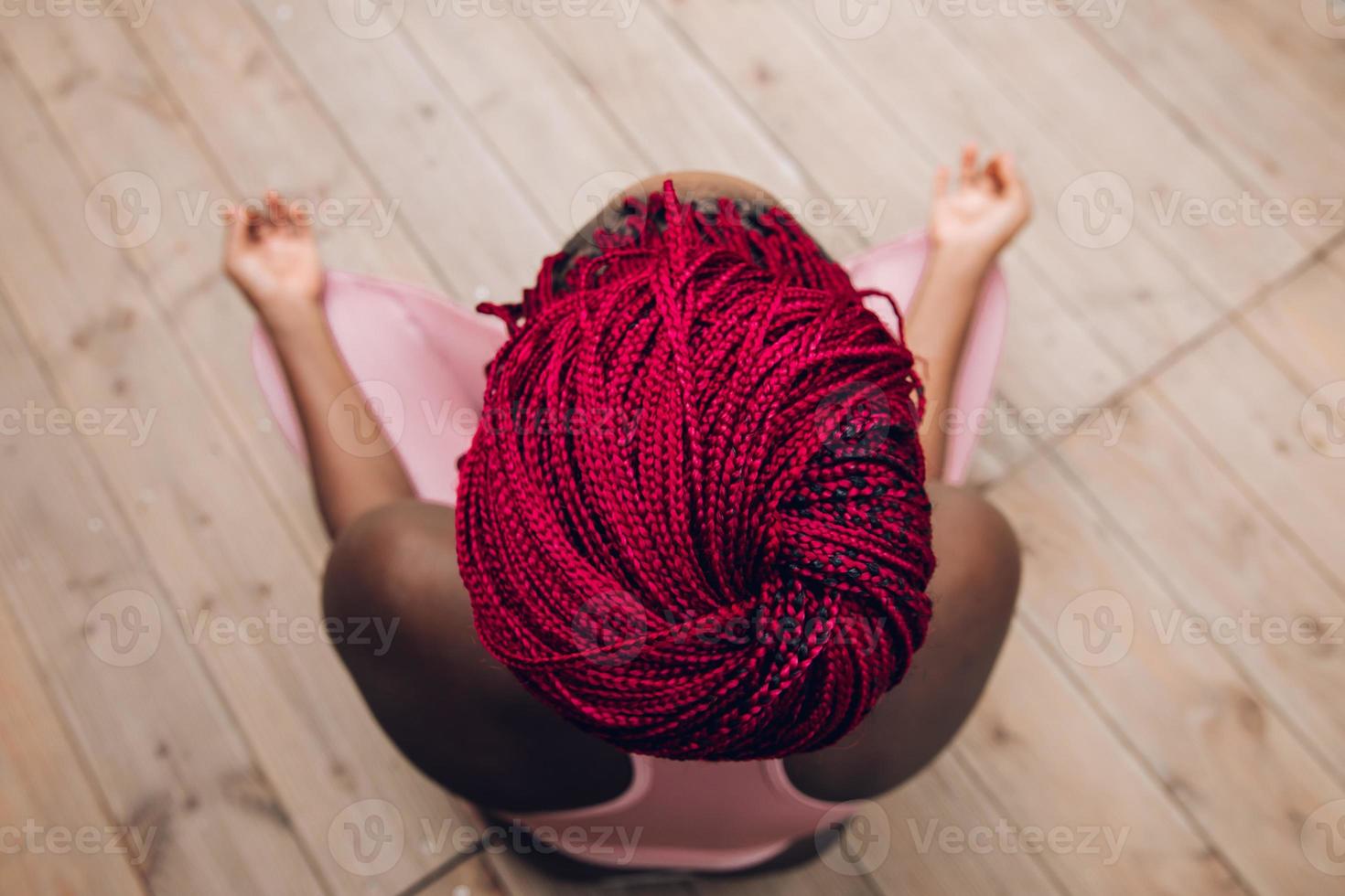 närbild av de röda flätorna av en kvinna som gör meditation foto