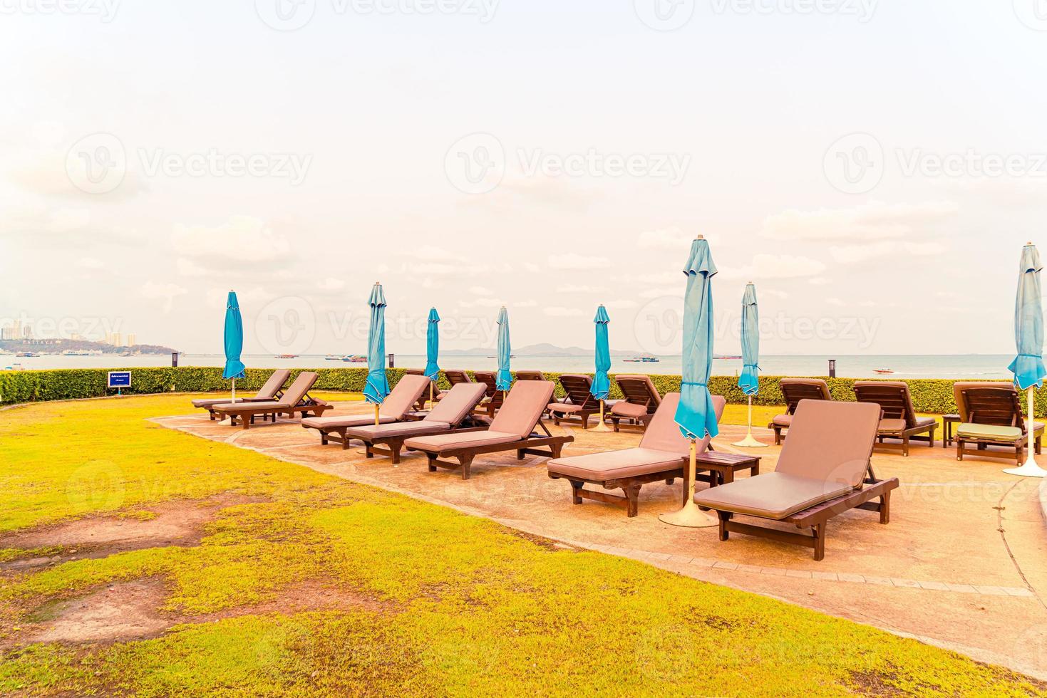 stol pool eller säng pool och paraply runt poolen med havet stranden bakgrund foto