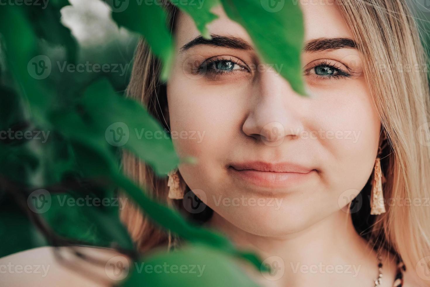 porträtt av en vacker blond tjej med naturlig skönhet i gröna löv träd. kopiera, tomt utrymme för text foto