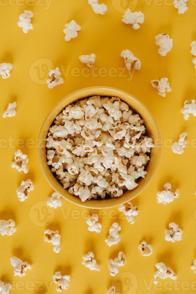 popcorn i en gul skål på en gul bakgrund. toppvy. kopiera, tomt utrymme för text foto
