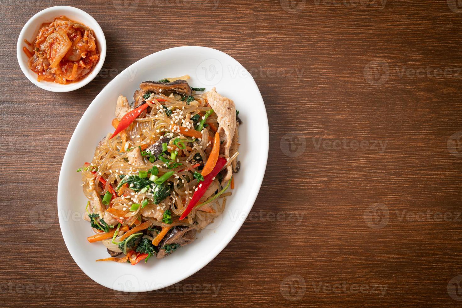 japchae eller wokade koreanska vermicelli nudlar med grönsaker och fläsk toppad med vit sesam foto