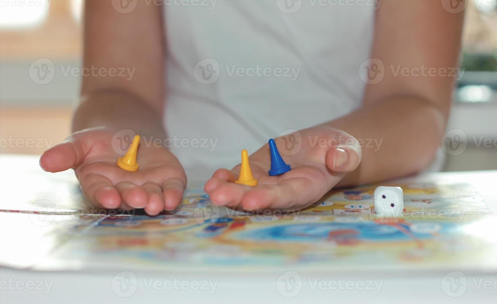 liten flicka spelar brädspel. spelmarker i flickans händer foto