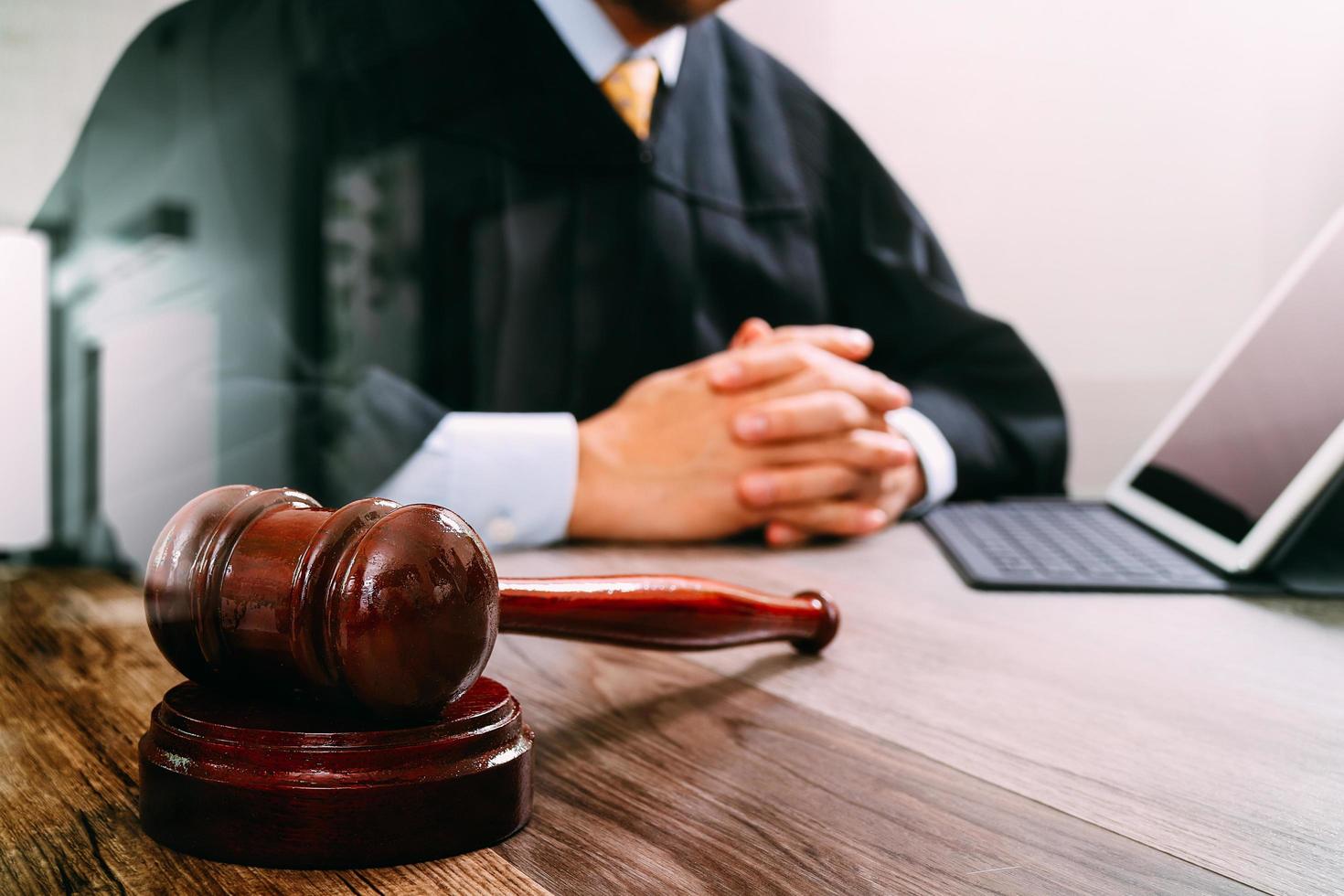 rättvisa och lag koncept. manlig domare i en rättssal med klubban, arbetar med digital surfplatta med dockningstangentbord på träbord, filtereffekt foto