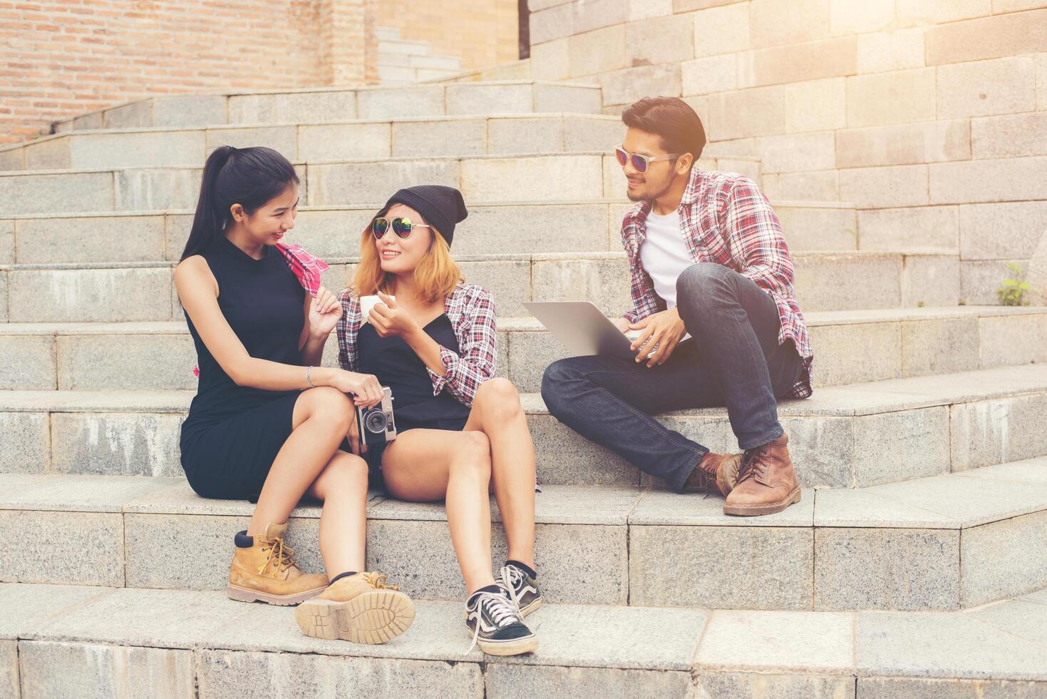 grupp hipsterstudenter som sitter på en trappa och pratar och kopplar av efter skolan tillsammans. foto
