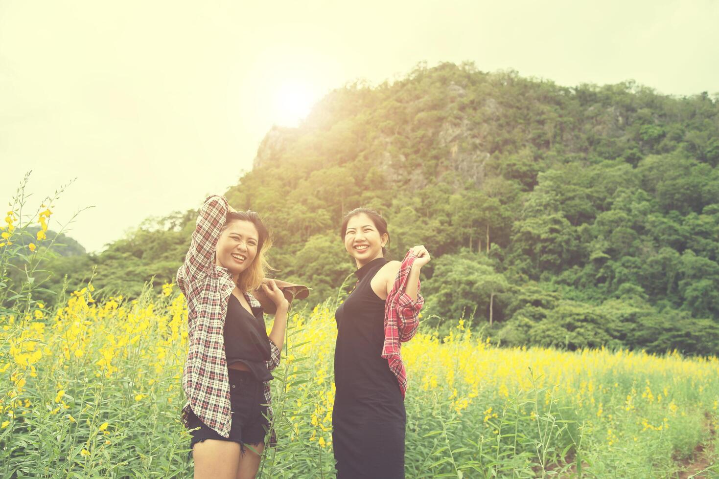 två hipster kvinna reser och njuter med blomma fält tillsammans, avkopplande god tid solig dag. foto