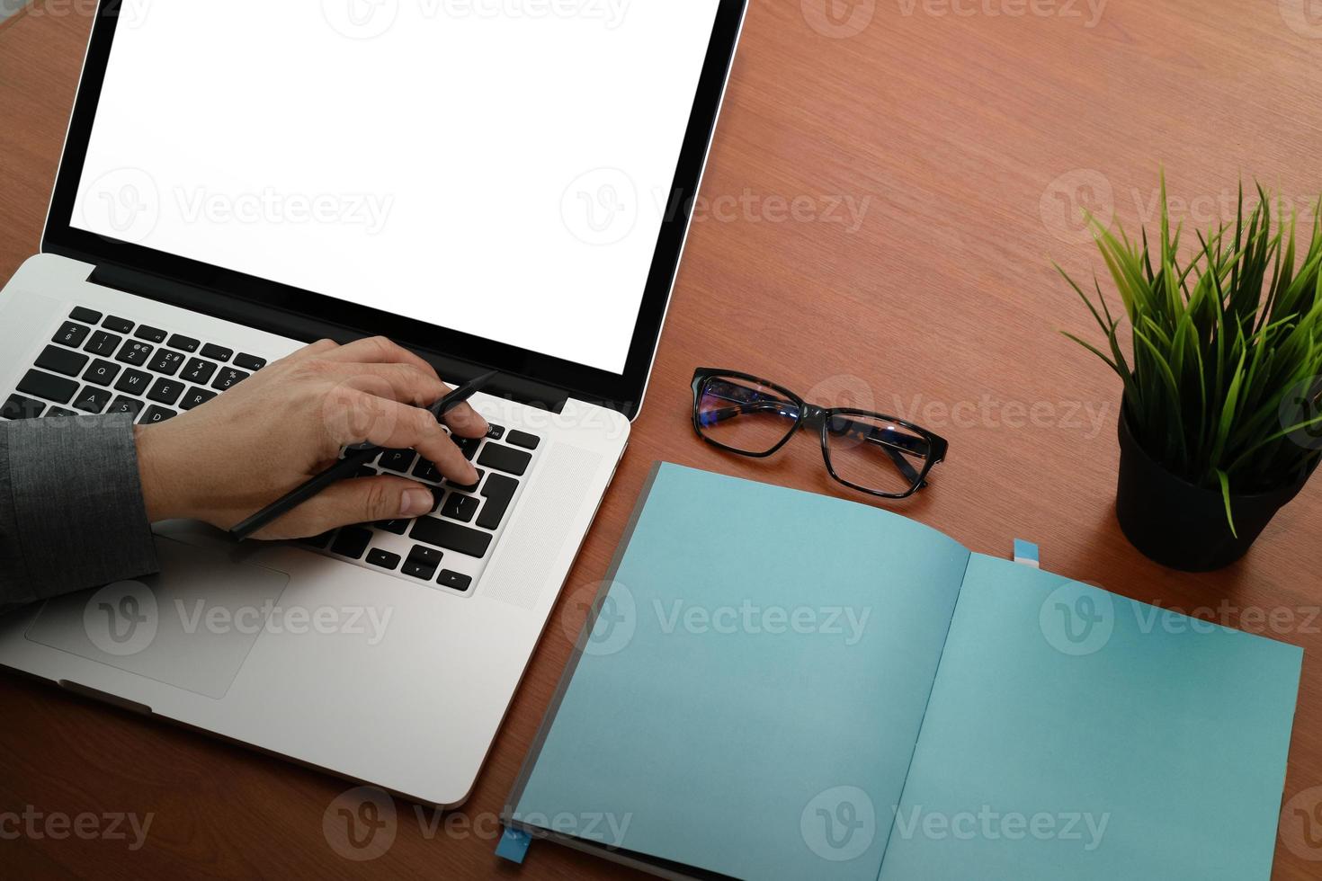 ovanifrån av affärsman hand som arbetar med ny modern tom skärm dator på tom bok på trä skrivbord som koncept foto