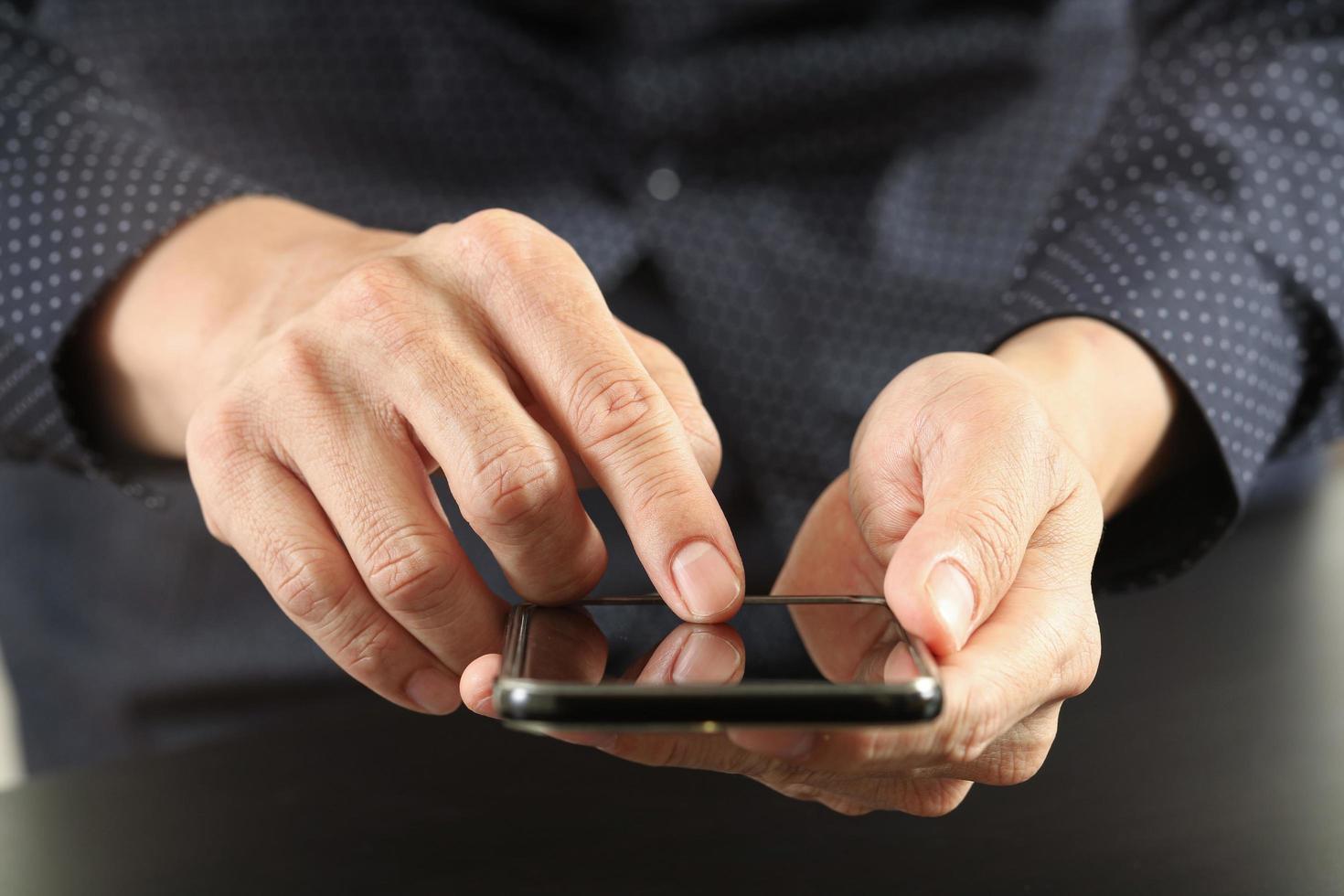 närbild av affärsman hand som arbetar med mobiltelefon i moderna kontor foto