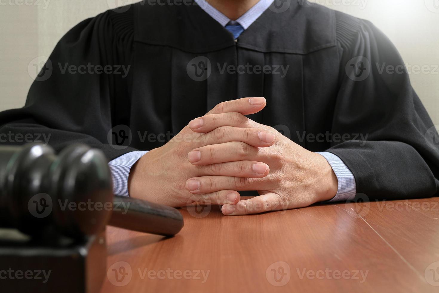 rättvisa och lag koncept. manlig domare i en rättssal slår klubban, arbetar med digital surfplatta med dockningstangentbord på träbord foto