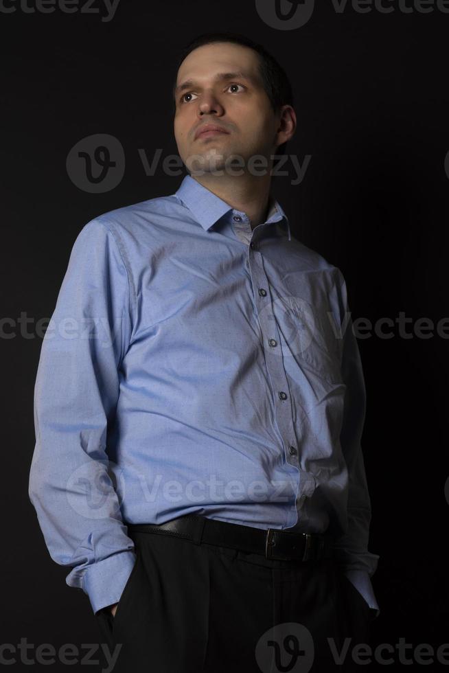 en man i en blå skjorta på en svart bakgrund. foto