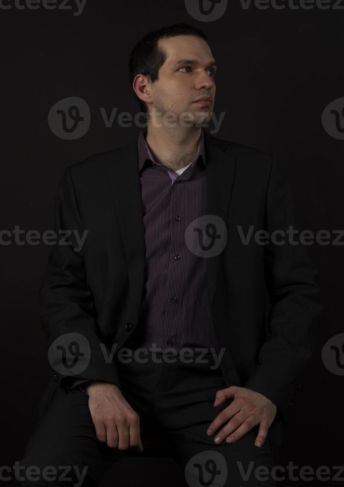 en man i svart kostym på en svart bakgrund. foto