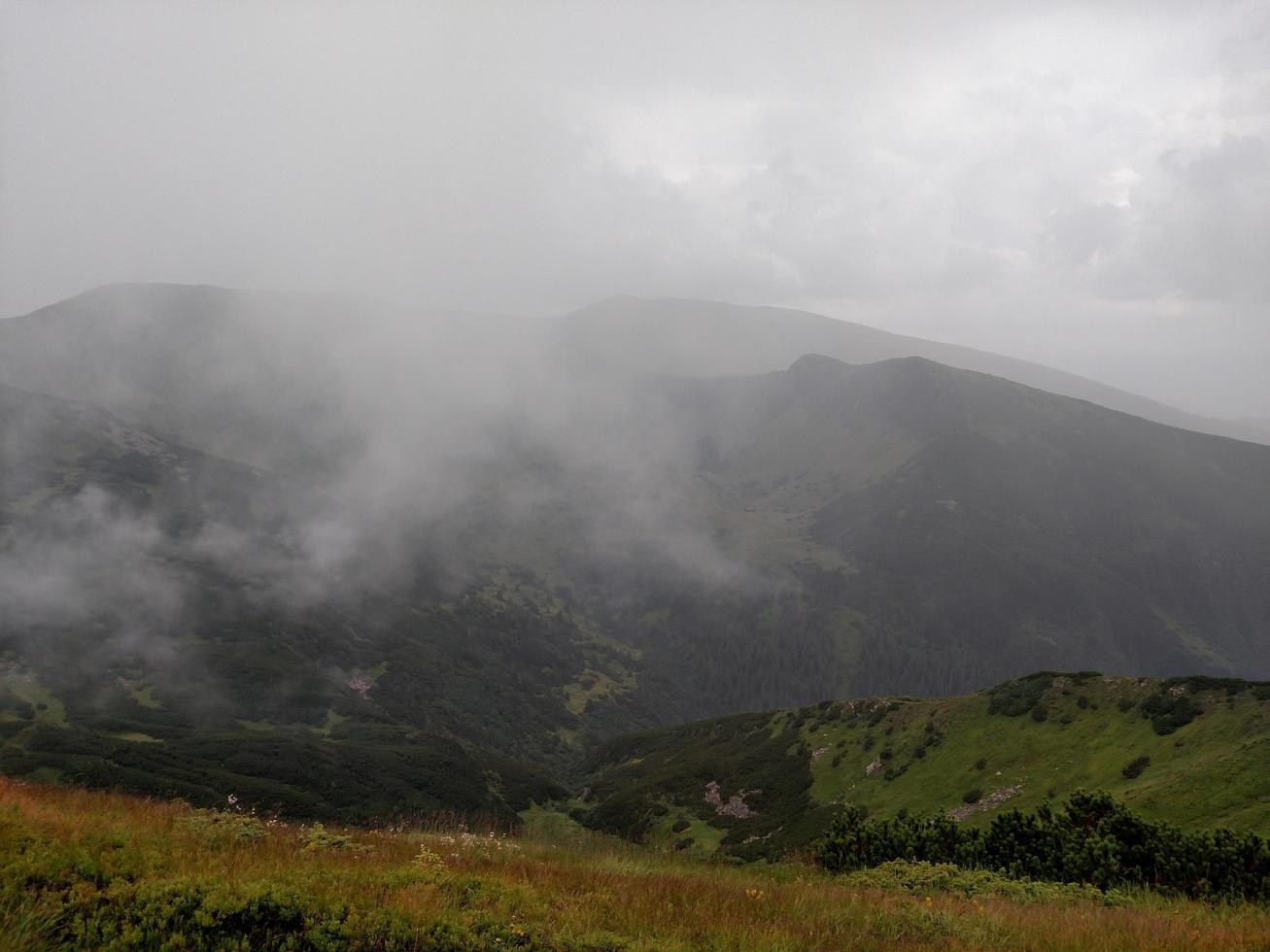 bergskedjor i molnigt väder nära sjön foto