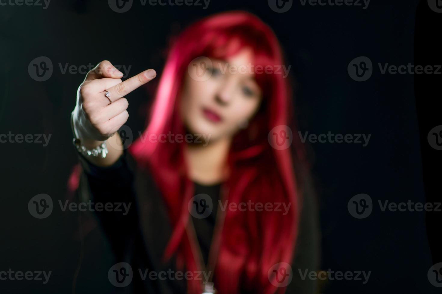 en flicka med rött hår gör långfingret foto