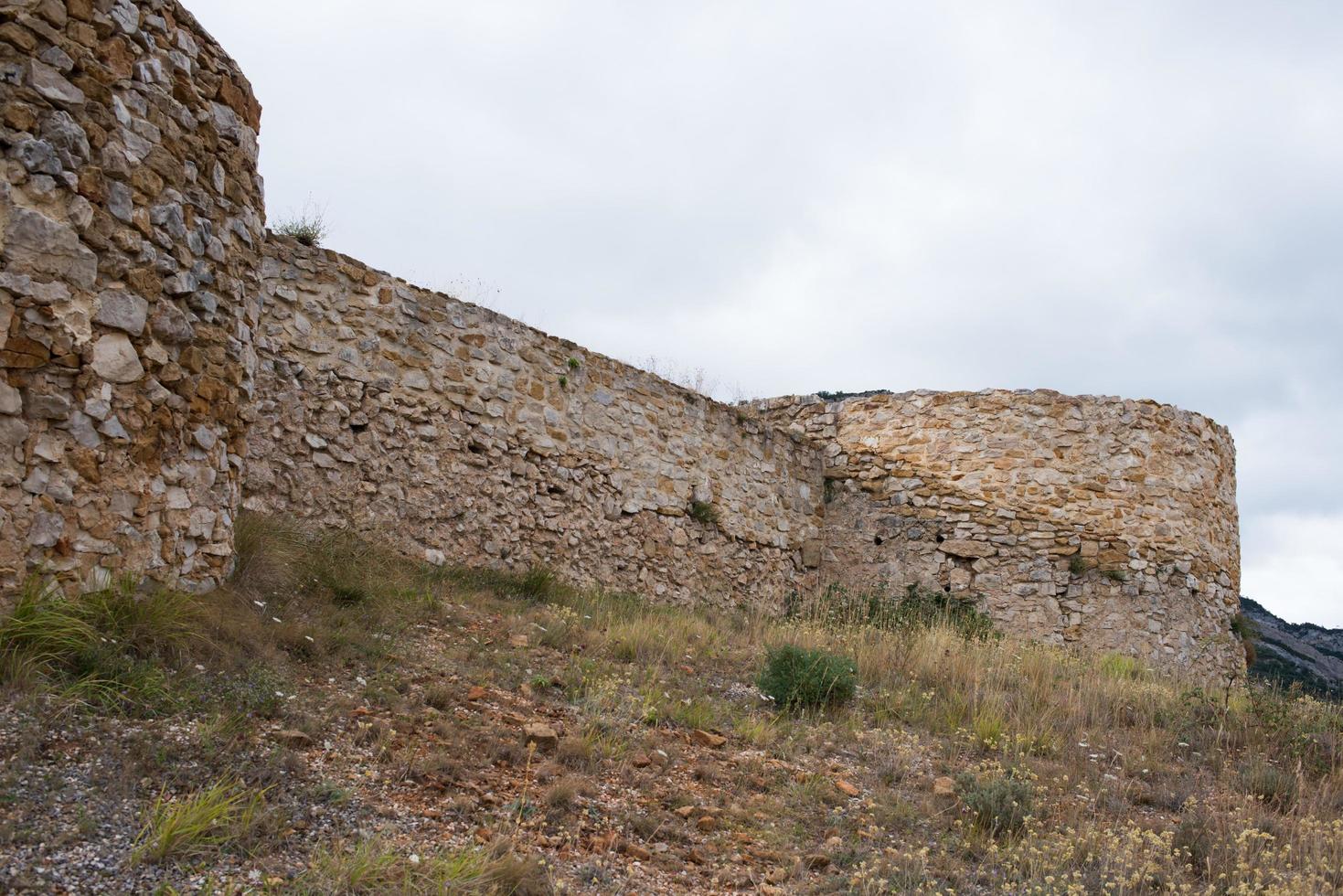 ruinerna av ett gammalt slott vid merindades, burgos, spanien. stenmurar och gräs runtom. foto